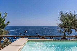 A pool with a view of the sea and boats.