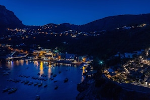 A coastal town at night with illuminated buildings and boats on the water.