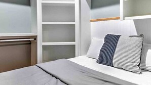 A bedroom with a bed, a bedside table, a wardrobe, and a mirror.