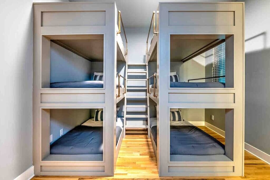 A dormitory-style room with bunk beds arranged in a central aisle.