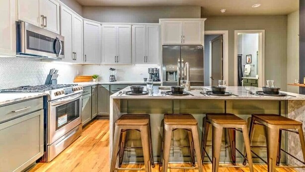 A modern kitchen with white cabinets, stainless steel appliances, and a central island with stools.