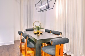 A dining table with six chairs, a chandelier, and a vase with flowers.