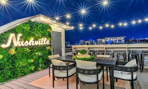 Eine Dachterrasse mit Außenbereich, einer grünen Wand mit dem Schriftzug 'Nashville' und einer Stadtkulisse im Hintergrund.