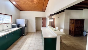 A kitchen with a wooden ceiling, green cabinets, a white countertop, and a tiled floor. - Newly updated 3BD 2BA House, close to Palm Beach, shops and dining (Noord)