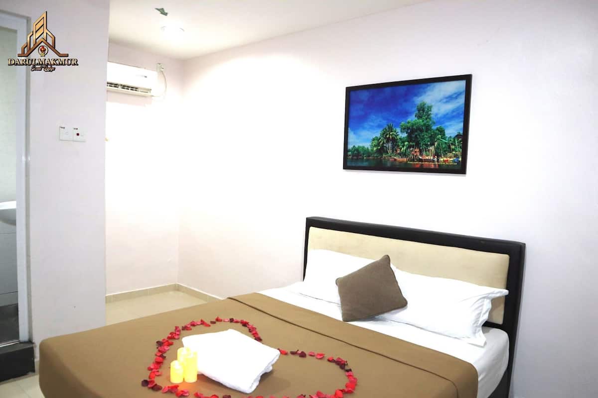 Une chambre d’hôtel avec un lit, un tableau représentant un paysage tropical et un logo sur le mur.