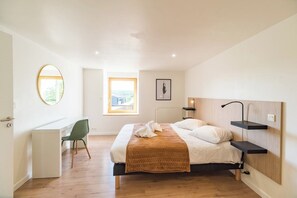 A modern bedroom with a bed, a desk, and a chair. There is a window with a view of the city. - Large house: billiards, garden, beaches 25 min (Saint-Carreuc)