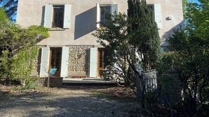 Un edificio de dos pisos con numerosas ventanas, una entrada de piedra y un camino de grava.