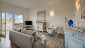 A living room with a sofa, a television, a cabinet, and a chair. - Villa Ulivi private Pool & Lake View (San Felice del Benaco)