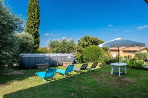 A backyard with a hot tub, lounge chairs, and a patio umbrella.