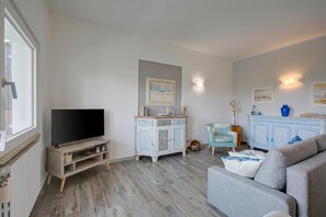 A living room with a TV, light blue cabinet, and grey sofa.