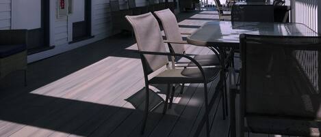 Un espacio al aire libre techado con piso de madera, sillas y una mesa.