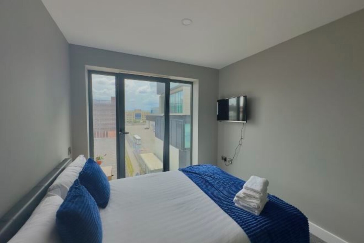 Ein Hotelzimmer mit Bett, Fernseher und Blick durch eine Glastür.