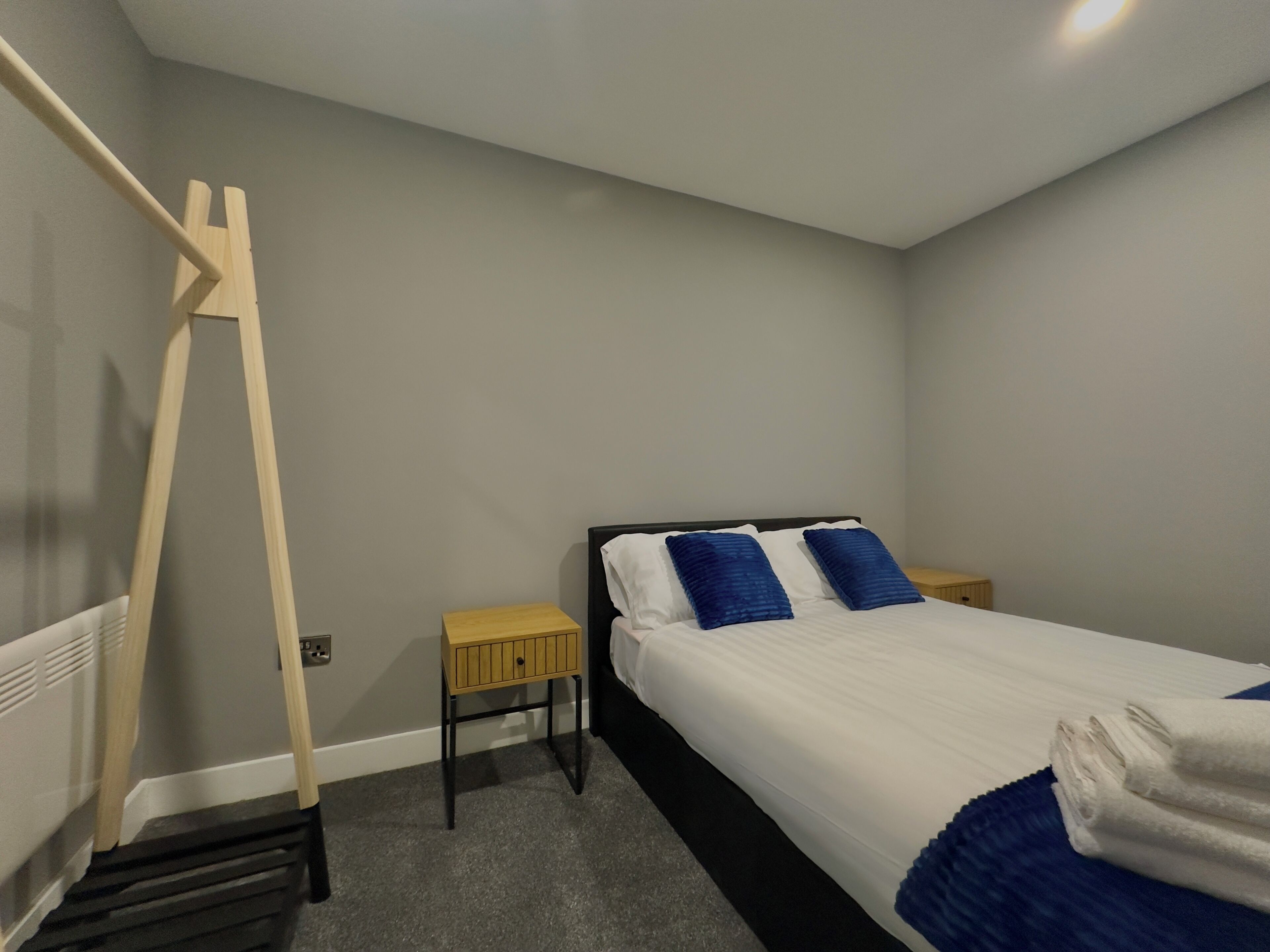 Une chambre à coucher avec un lit, une échelle en bois, une table de chevet et une petite armoire.