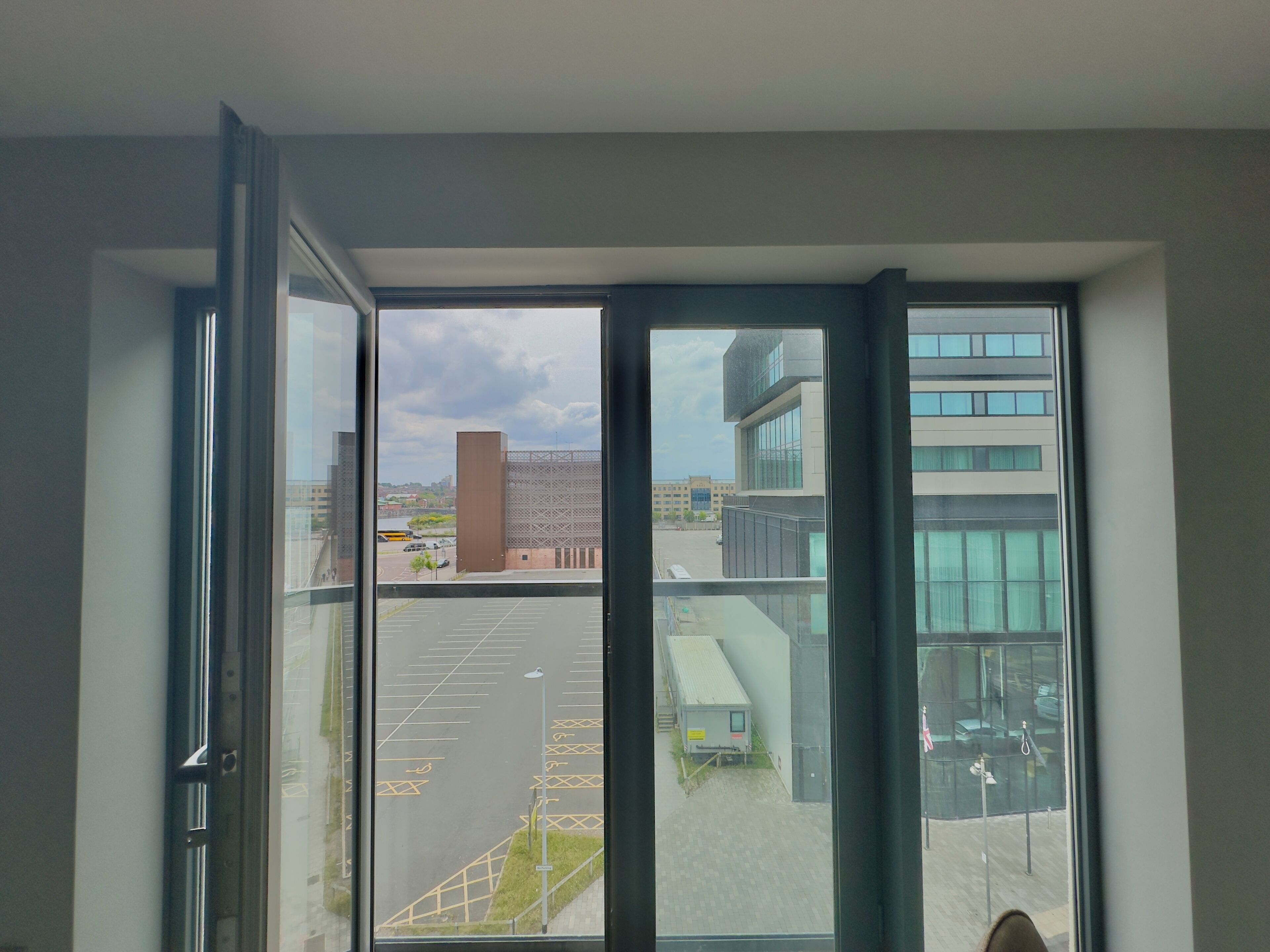 A view through a large window of a parking lot and buildings.