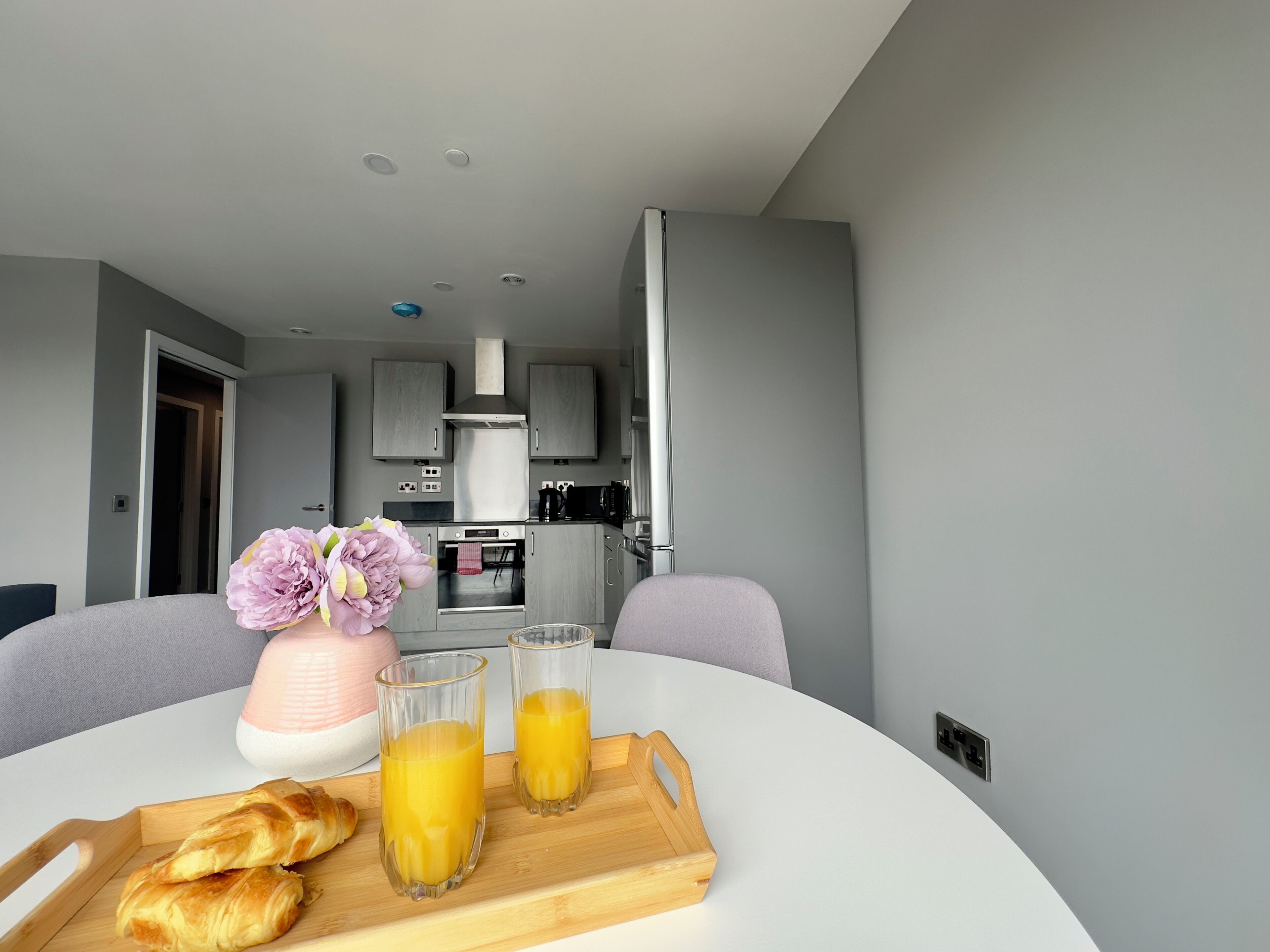 A modern kitchen with grey cabinets, a stainless steel range hood, and a coffee machine.