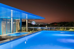 A modern outdoor pool area with a clear view of a Ferris wheel in the background. - Lux Retreat - Waterfront Gym Prime Location (Cairns)
