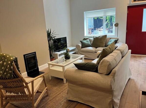 Una sala de estar con un sofá, una televisión, una mesa de centro y un sillón.