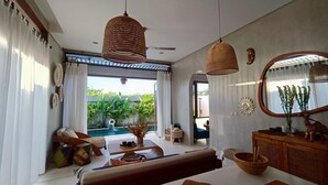 A modern living room with a pool view, wicker hanging lights, and a large mirror. - A private 200sqm entire villa, pool & rooftop with rice field view (Bali)