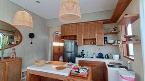 A modern kitchen with wooden cabinets, a stainless steel refrigerator, and two hanging light fixtures. - A private 200sqm entire villa, pool & rooftop with rice field view (Bali)