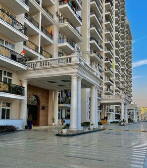 Un hotel de varios pisos con una entrada imponente, varios balcones y un amplio patio.