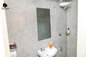 Une salle de bain avec un grand miroir, un lavabo, une douche et un porte-serviettes.