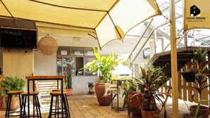 Een binnenterras met zithoek, potplanten en een bord met de tekst 'Cedar Serene Studio Apartments'.
