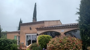 Una casa con camino de entrada de grava, césped verde y un jardín bien cuidado con diversas plantas y flores.