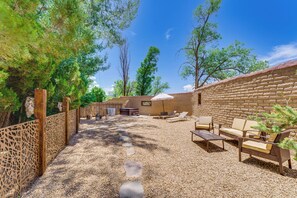 A patio area with outdoor seating, a barbecue grill, and a brick wall.