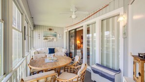 A cozy room with a round wooden table, wicker chairs, a sofa, and a ceiling fan. - Pool Access & Lanai: Riverfront Welaka Condo! (Welaka)