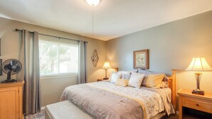 A bedroom with a bed, bedside tables, a fan, and a window with curtains. - Pool Access & Lanai: Riverfront Welaka Condo! (Welaka)