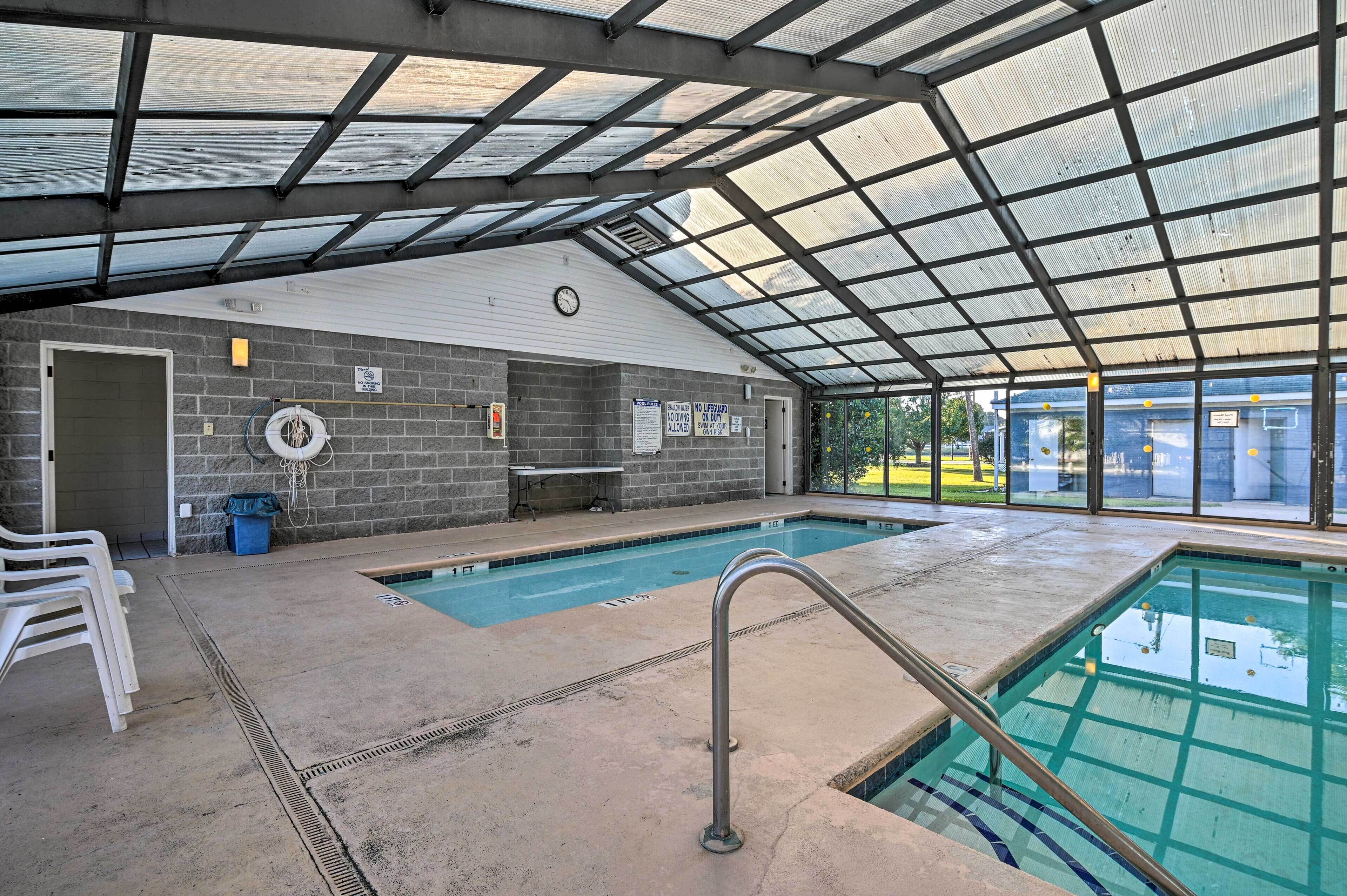 An indoor swimming pool with a covered roof, a clock on the wall, and a lifeguard chair.