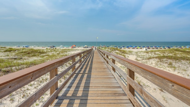 A wooden boardwalk leading to a beach with umbrellas and beach chairs. - Beachy Gulf Shores Condo w/ Pool, Walk to Shore! (Gulf Shores)