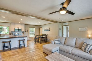 A modern kitchen with a central island, wooden flooring, and a ceiling fan.