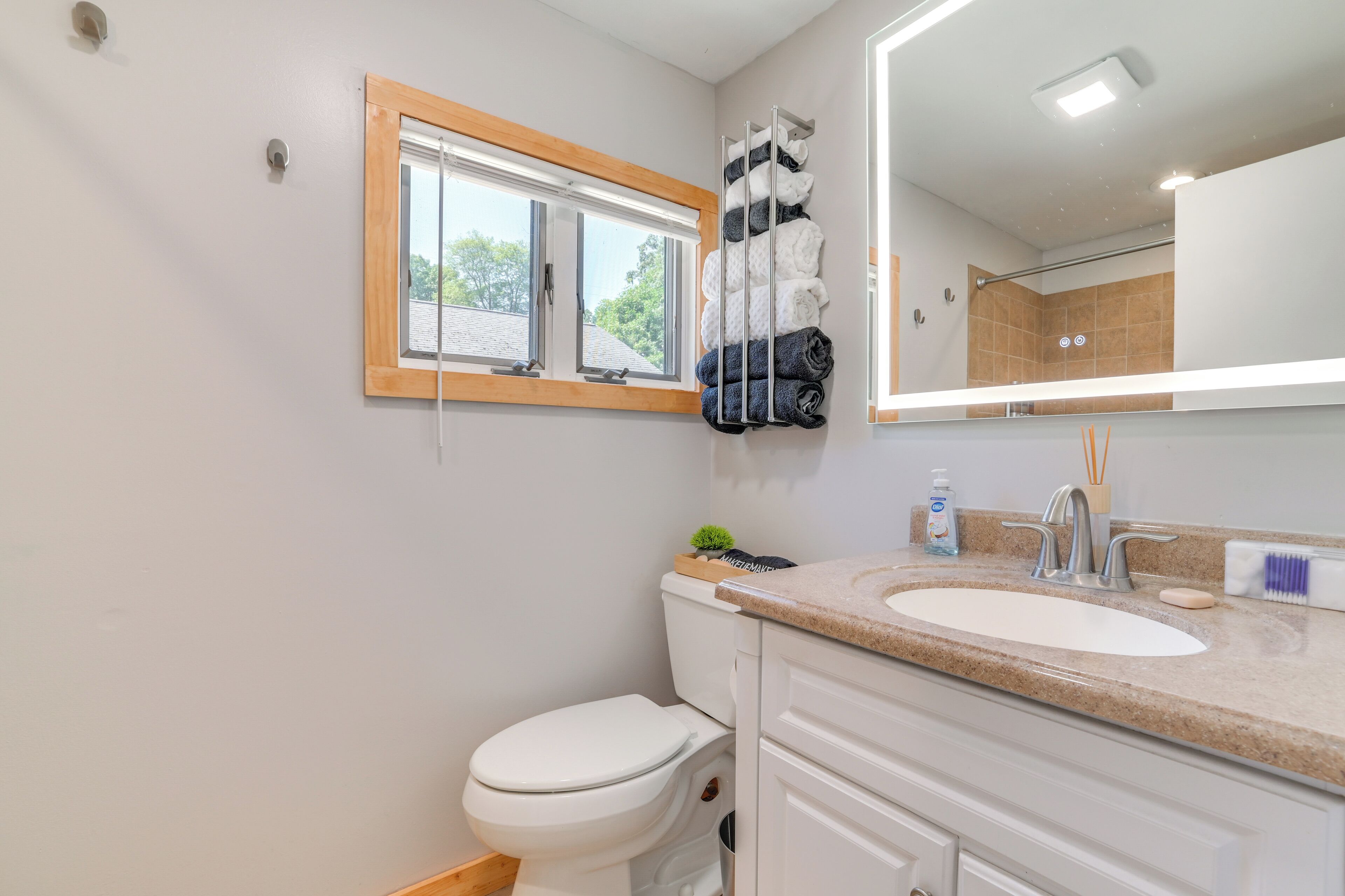 A modern bathroom with a toilet, sink, and a window.