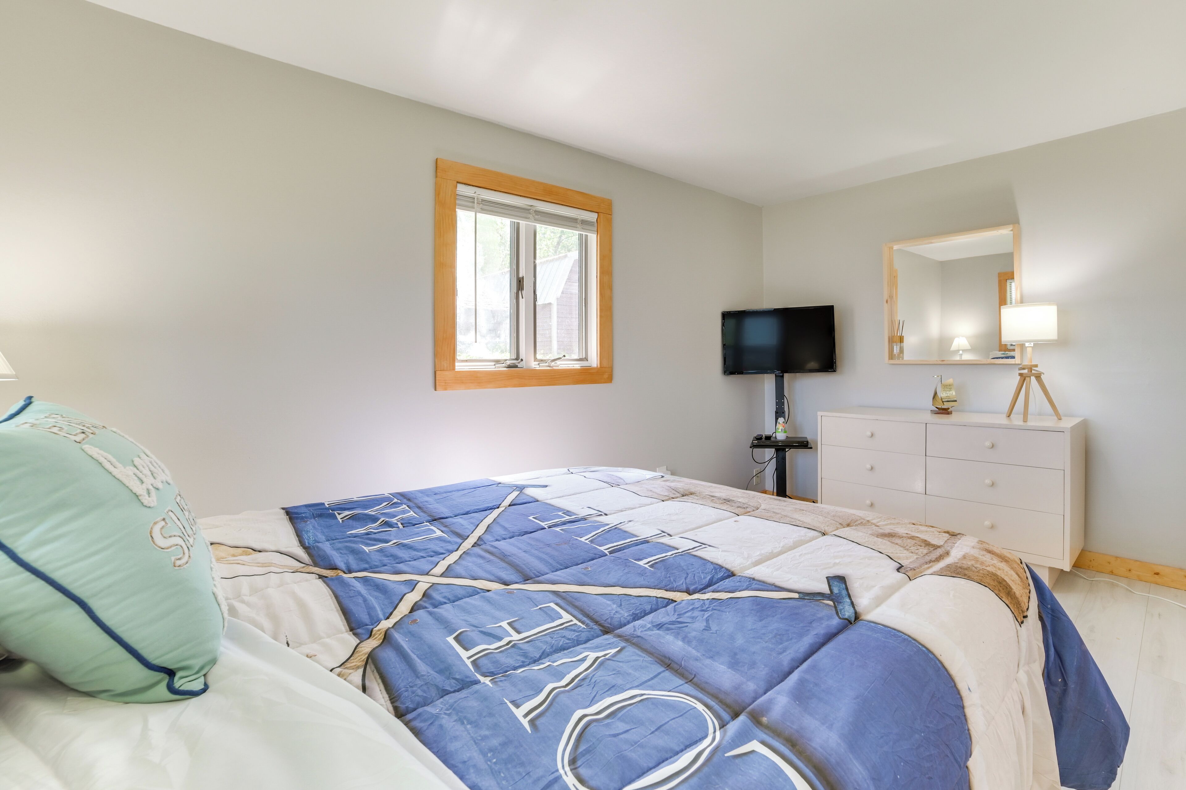 A bedroom with a bed, a television, a dresser, and a window.
