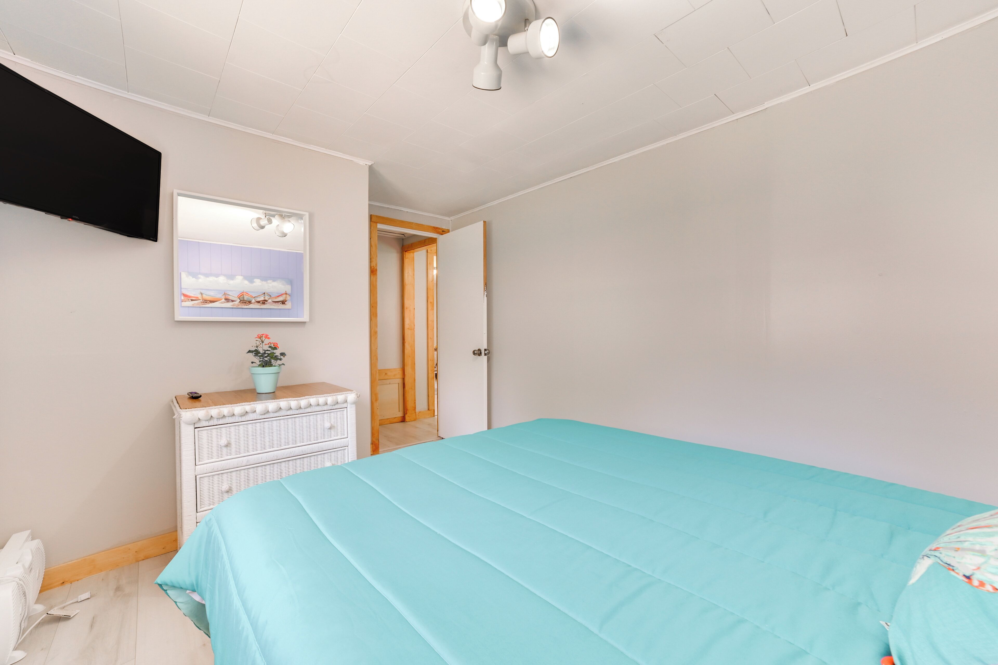 A bedroom with a bed, dresser, and a painting on the wall.