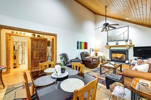 A spacious living room with a fireplace, leather sofas, a dining area with a wooden table, and a ceiling fan. - Idyllic Sylva Cabin w/ Great Smoky Mountains View! (Sylva)