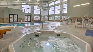 Ein großes Hallenbad mit einer Hottub-Anlage in der Mitte, umgeben von Fenstern und einer Sitzecke.