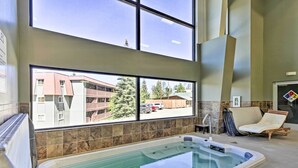 Ein Wellnessbereich mit Whirlpool, einem Fenster mit Blick auf Gebäude und einem Sessel.