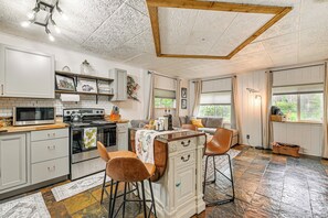 A kitchen with a central island, bar stools, a stove, and a microwave. - Sterling Home w/ Patio, BBQ Grill & Fire Pit! (Sterling)