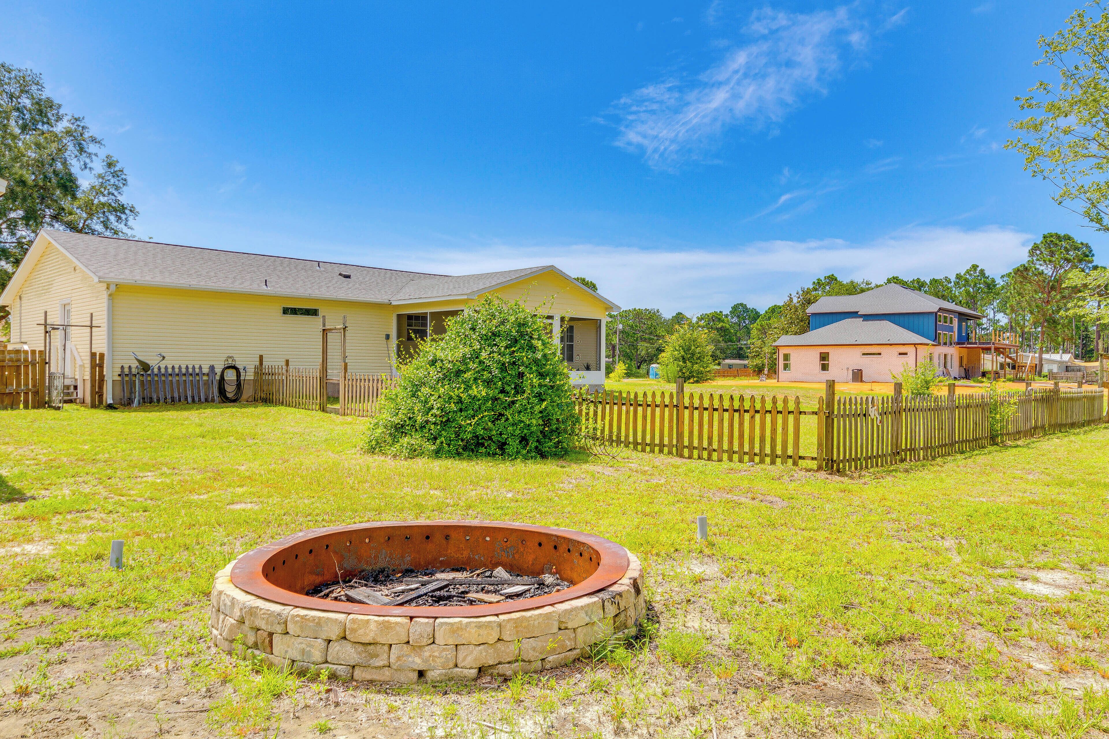A residential area with a house, a fire pit, and a fenced yard.