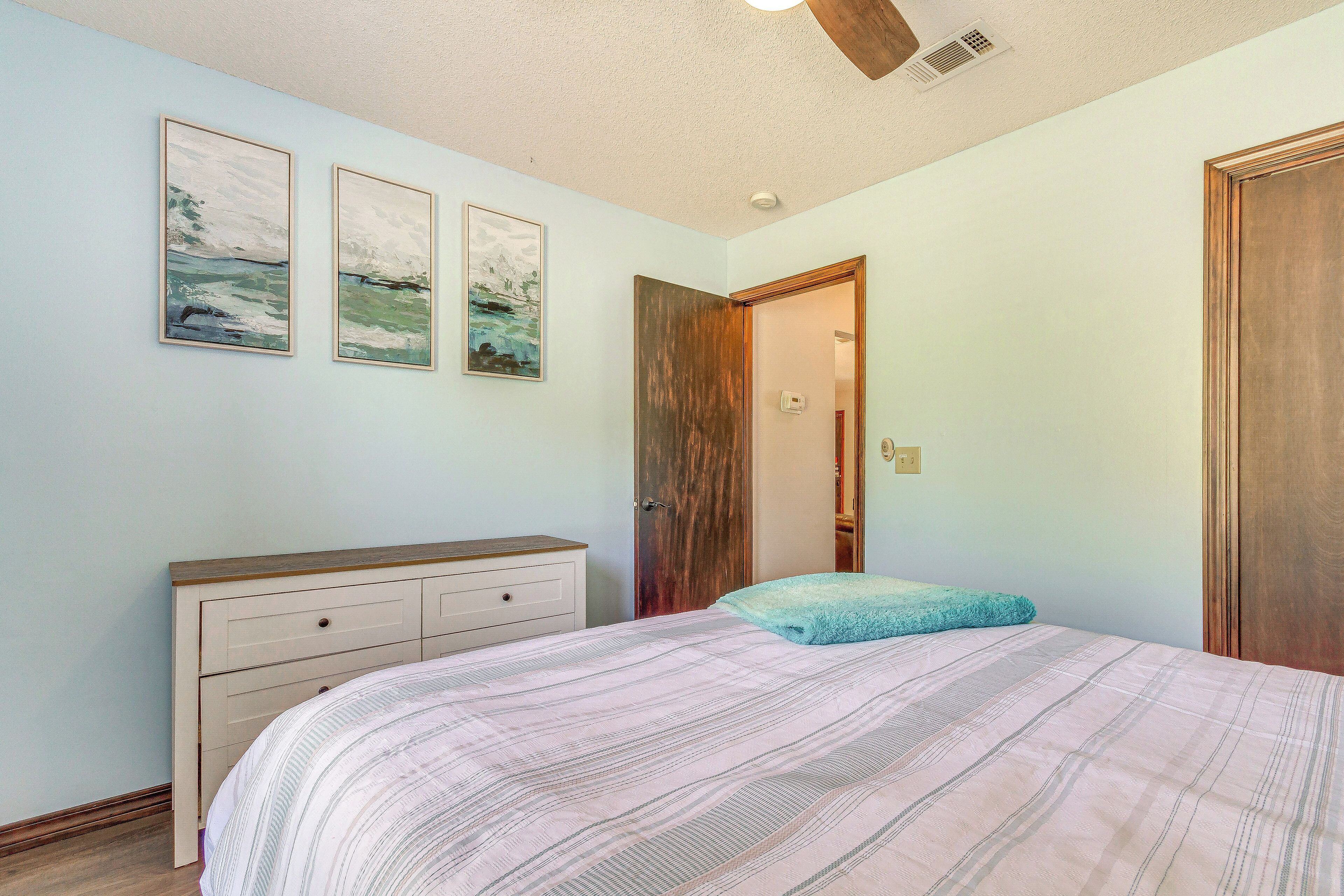 A bedroom with a bed, a dresser, and a door.
