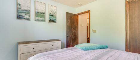 A bedroom with a bed, a dresser, and a door.