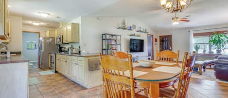 A spacious kitchen with wooden cabinets, a dining table with chairs, and a chandelier.