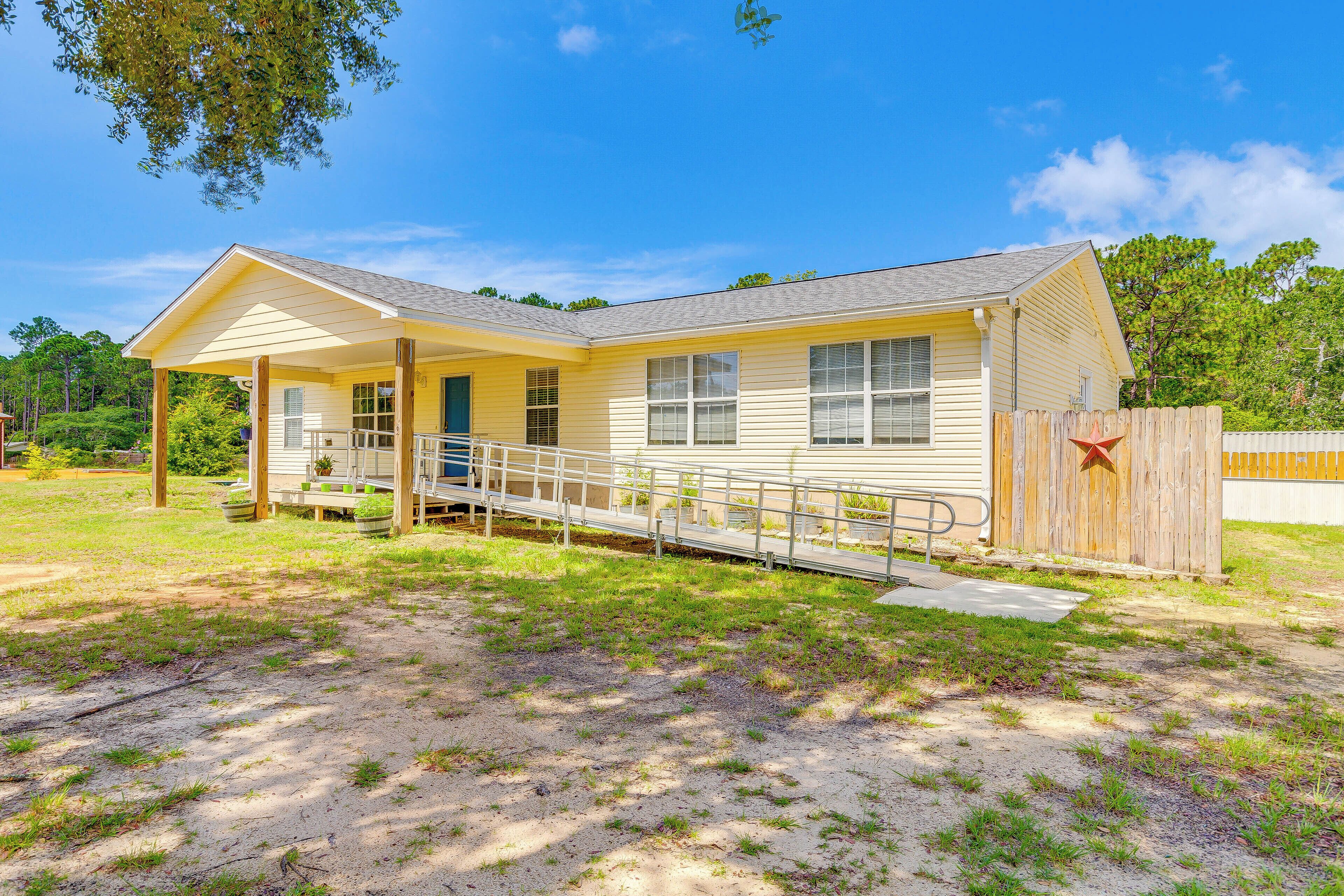 A single-story yellow building with a covered porch, a wheelchair ramp, and a fenced area.