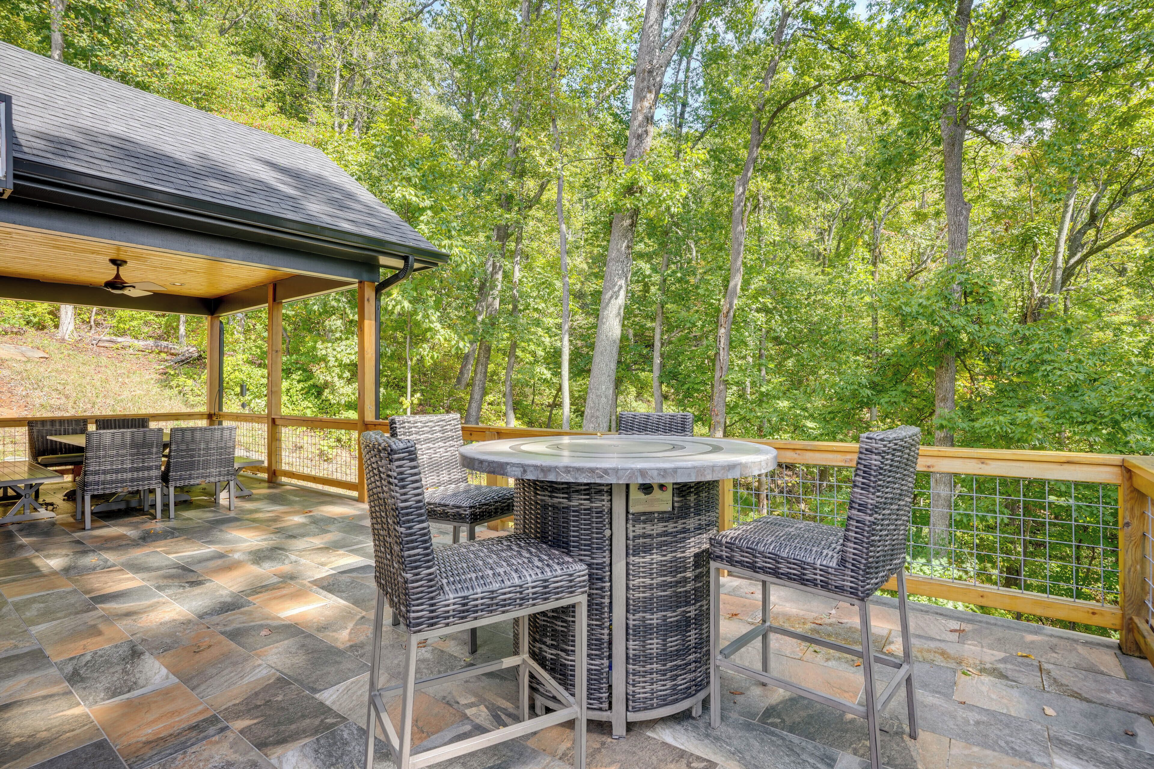 Een terras buiten met rieten meubels, een ronde tafel en een pergola.