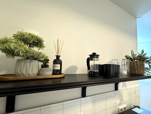 A kitchen counter with a potted plant, a bottle of reed diffuser, a coffee maker, and a glass pitcher. - Day Dream L23 Guesthouse (Reykjavik)