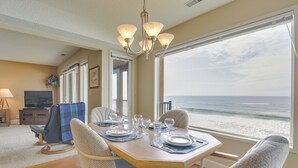 A dining area with a view of the ocean, a television, and a cozy seating arrangement.
