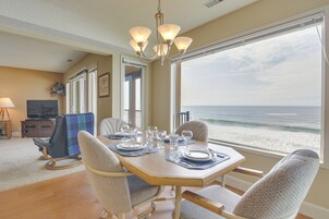 A dining area with a view of the ocean, a television, and a cozy seating arrangement.