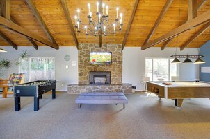 A spacious living area with a foosball table, a pool table, and a stone fireplace.